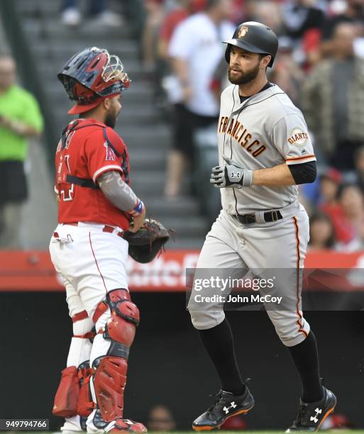 First baseman Brandon Belt of the San Francisco Giants crosses the plate in front of catcher Rene Rivera of the Los Angeles Angels of Anaheim after...