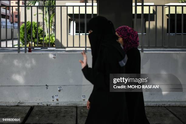 Pedestrians walk past a bullet-riddled wall at the scene where Palestinian scientist Fadi Mohammad al-Batsh was gunned down April 21 in what his...