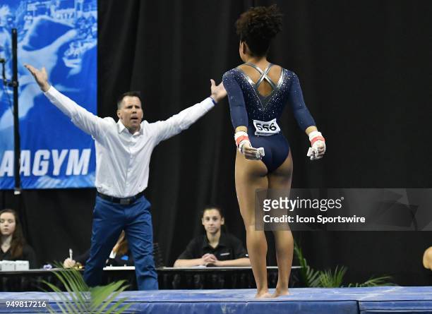 Assistant coach Chris Waller congratulates JaNay Honest of UCLA after her performance on the bars during the NCAA Women's Gymnastics National...