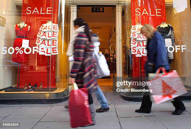 Shoppers pass a ladies fashion store advertising sales discounts in London, U.K., on Saturday, Dec.19, 2009. Shoppers hit the high street in force...