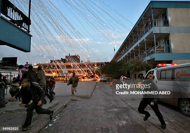Palestinian civilians and medics run to safety during an Israeli strike over a UN school in Beit Lahia, northern Gaza Strip early on January 17,...