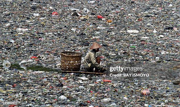 Man scavenges through a polluted river in Jakarta, 05 September 2004. Hundreds of meter squares of garbage are floating on many rivers in the...