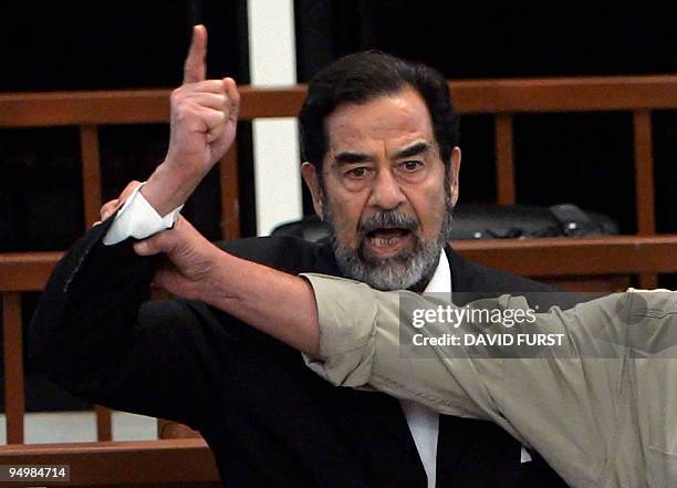 Former Iraqi President Saddam Hussein yells at the court as a bailiff attempts to silence him during the delivery of his verdict in his trial held...