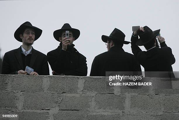Ultra-Orthodox Jewish men stand on the rooftop of a Palestinian house as they visit with fellow believers and setters the Jewish shrine of Atnaeil...