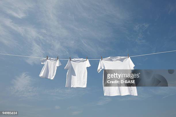 white t-shirts in a row on washing line. - white laundry foto e immagini stock