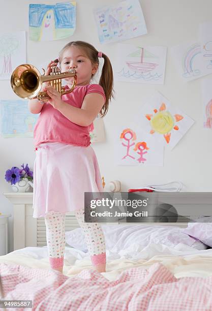 young girl playing trumpet, standing on bed - trumpet stockfoto's en -beelden