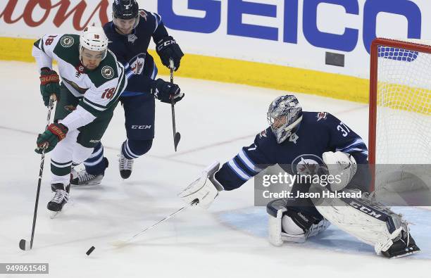 Jordan Greenway of the Minnesota Wild tries to get a shot away under pressure from Jacob Trouba and Connor Hellebuyck of the Winnipeg Jets kljlkjlkjk...