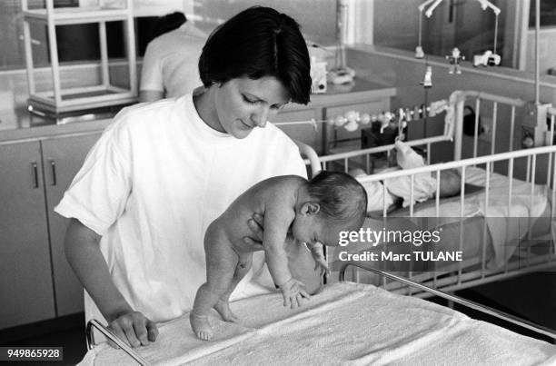 Kinésithérapeute s'occupant d'un bébé dans la maternité de l'hôpital Debrousse à Lyon, dans le Rhône, en mai 1979, France.