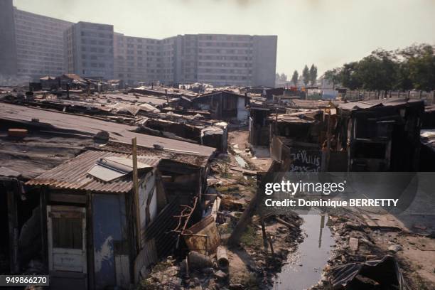 Lers habitations precaires d'un bidonville de la banlieue parisienne, devant de nouveaux immeubles construits afin d'offrir de meilleurs conditions...