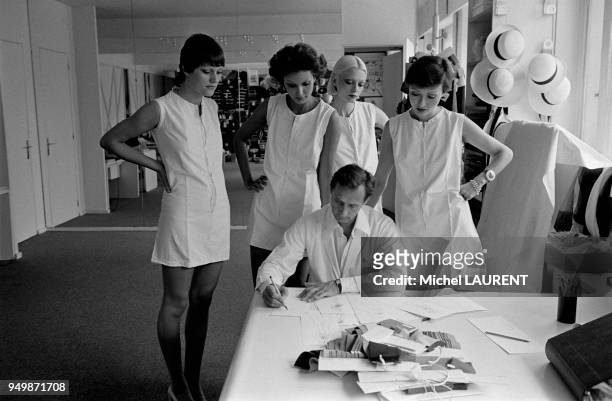 Le styliste de la maison Dior Marc Bohan entouré de mannequins lors d'une séance de travail en juillet 1973 à Paris, France.