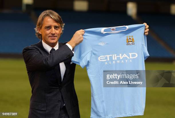 Roberto Mancini the new manager of Manchester City holds up a Manchester City shirt during a photocall after a press conference held at the City of...