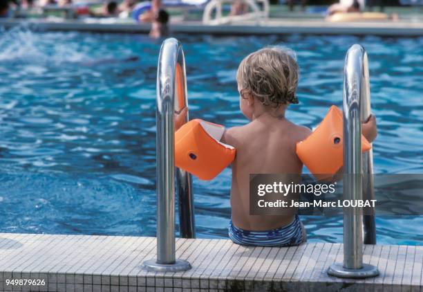 Enfant apprenant la natation dans une piscine en France.