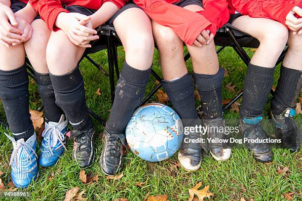 girls' soccer team on bench with soccer ball - change socks stockfoto's en -beelden