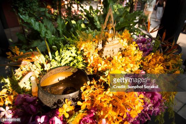 buddha statue and flowers for bathing ritual during songkran festival - sunphol stock-fotos und bilder
