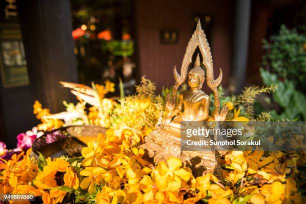 buddha statue and flowers for bathing ritual during songkran festival - sunphol stock-fotos und bilder