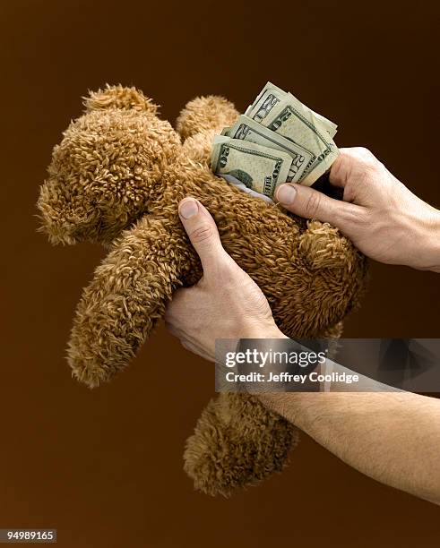 man stuffing teddy bear with money - hiding money stock pictures, royalty-free photos & images