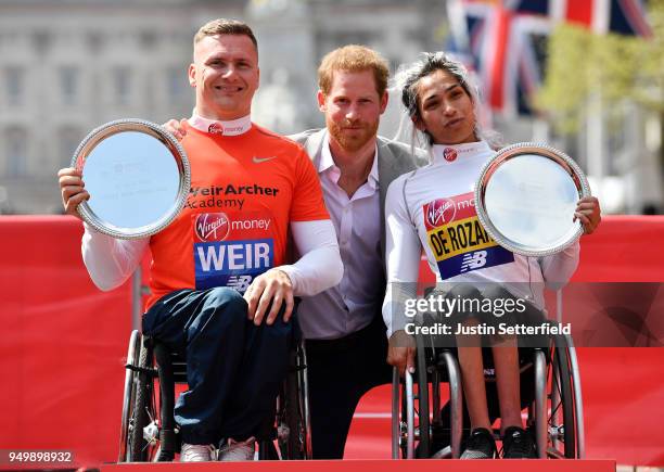 Prince Harry poses with David Weir of Great Britain and Madison de Rozario of Australia as they receive their trophies, following their first place...