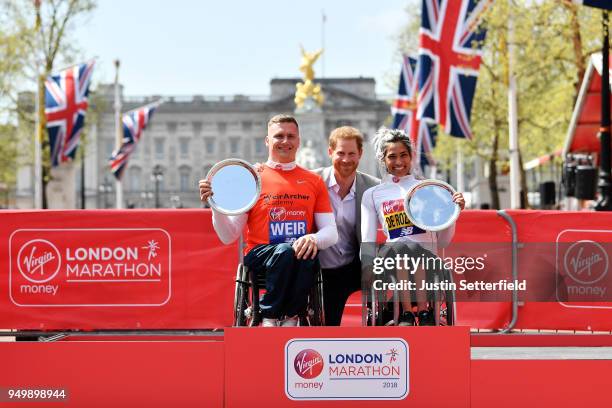 Prince Harry poses with David Weir of Great Britain and Madison de Rozario of Australia as they receive their trophies, following their first place...