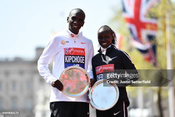 Eliud Kipchoge and Vivian Cheruiyot of Kenya pose as they receive their trophies, following their first place results during the Virgin Money London...