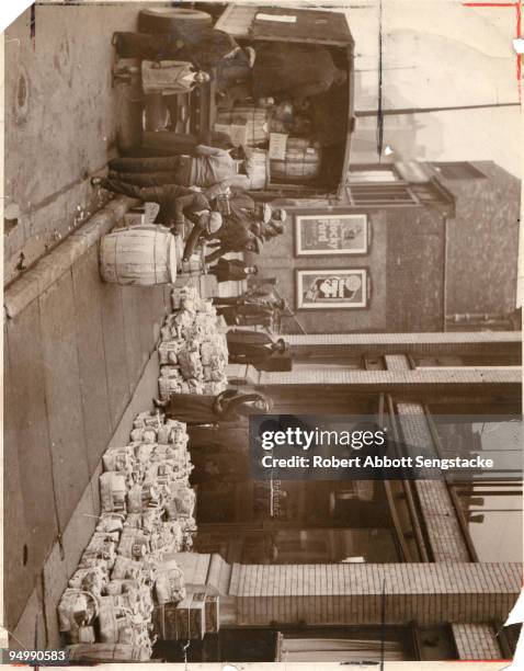 Outside the original Chicago Defender building, newspaper founder Robert Sengstacke Abbott stands amidst bundles of donations to be given out as...