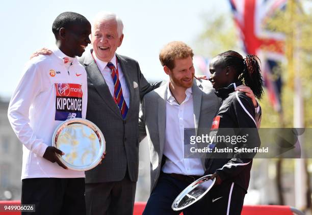 Prince Harry poses with Eliud Kipchoge of Kenya and Vivian Cheruiyot of Kenya as they receive their trophies, following their first place results...