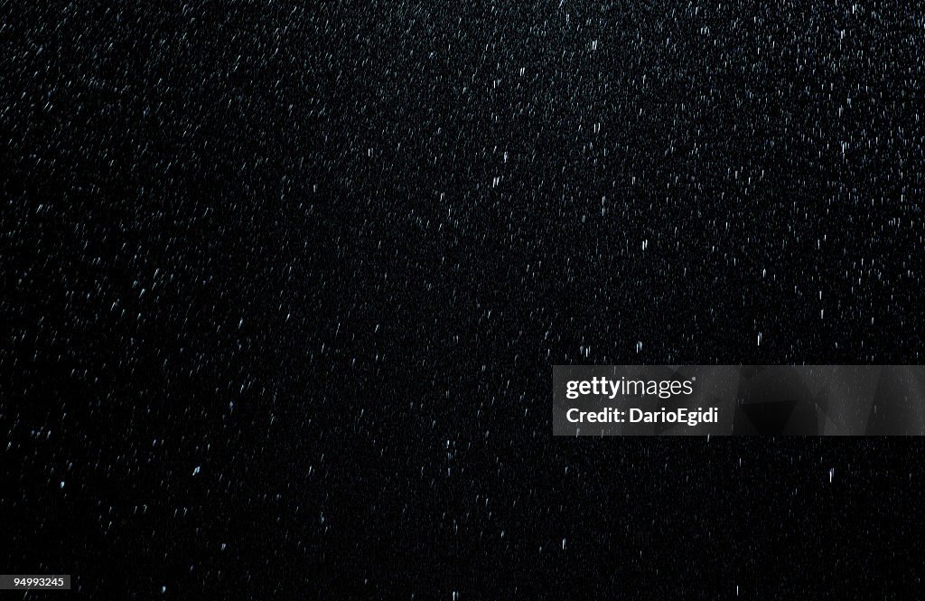 Raindrops falling down on black background