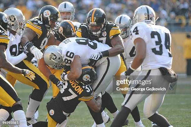 Linebacker Keyaron Fox of the Pittsburgh Steelers tackles tight end Tony Stewart of the Oakland Raiders with assistance from teammates Anthony...