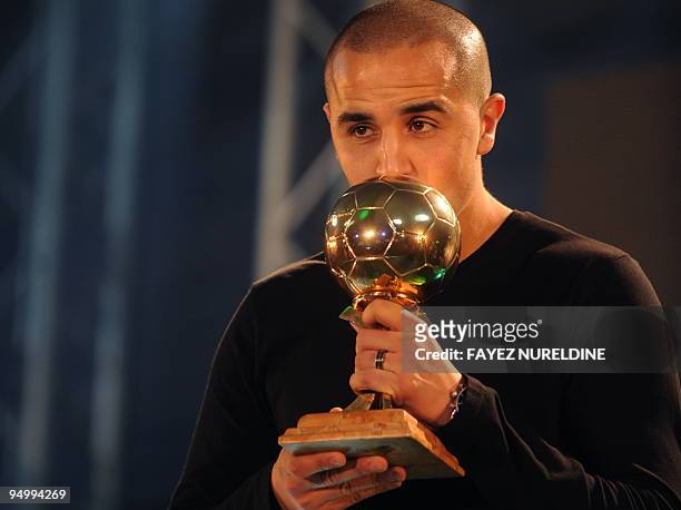 Algerian national and Scotland's Ranger team football player Madjid Bougherra kisses his 'Golden Ball' trophy of best Algerian player for 2009 during...