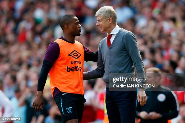 Arsenal's French manager Arsene Wenger greets West Ham United's French defender Patrice Evra on the touch line during the English Premier League...