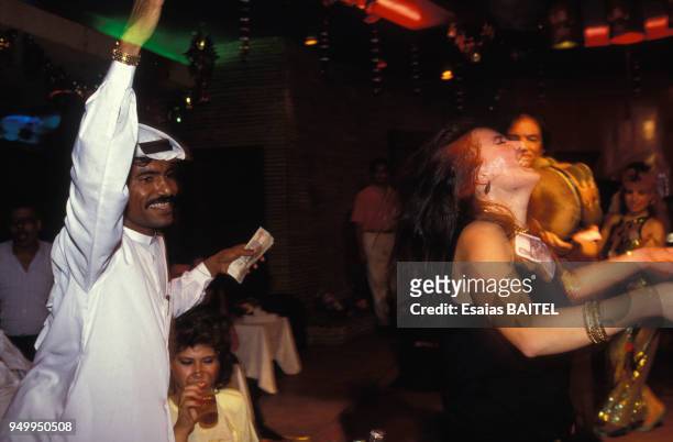Un client saoudien avec de l'argent en main s'approche d'une danseuse du ventre au cabaret Palmyra en juillet 1991 au Caire, Egypte.