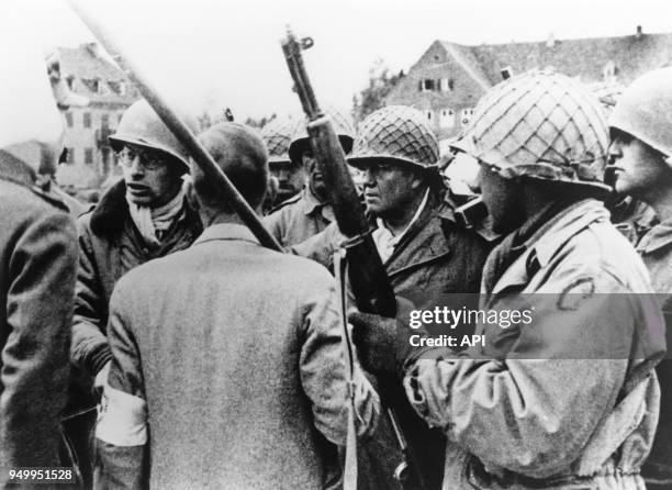 Soldats américains entourant un prisonnier lors de la libération du camp de concentration de Dachau en avril 1945, Allemagne.