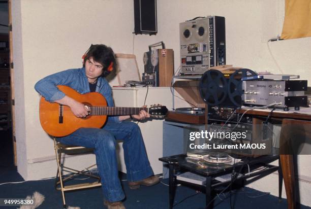 Portrait de Daniel Guichard entrain de composer sur sa guitare, circa 1970, en France.