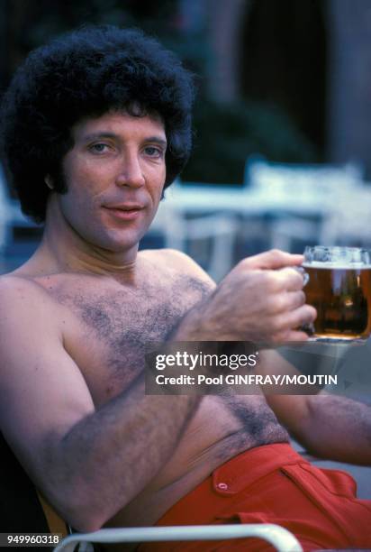 Le chanteur Tom Jones boit une bière au bord de sa piscine en décembre 1976 à Beverly Hills, Etats-Unis.
