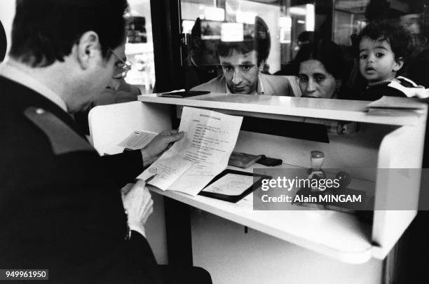 Un agent contrôle les papiers d'immigrés en provenance d'Algérie dès leur arrivée à l'aéroport de Marseille en décembre 1982 en France.