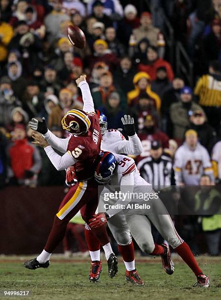 Punter Hunter Smith of the Washington Redskins throws an interception on a fake field goal in the second quarter as he is hit by Mathias Kiwanuka of...