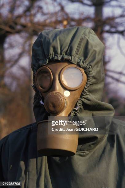 Equipé d'une combinaison et d'un masque à gaz lors d'une simulation d'attaque aérienne chimique sur la base de Nancy-Ochey le 12 mars 1987, France.