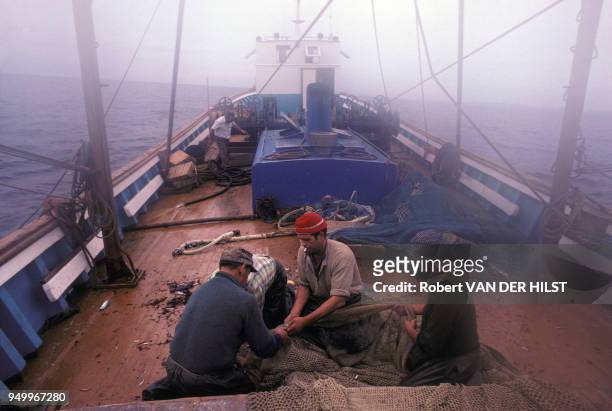 Marins pêcheurs réparant un filet à bord d'un chalutier en octobre 1979.