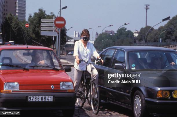 Cycliste portant un masque pour se proteger de la pollution en été à Paris, France.