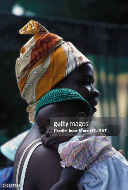Une femme porte sa petite fille endormie dans ses bras en juin 1980 au Gabon.