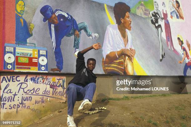 Un jeune homme entrain de danser le smurf devant une fresque murale à la Cité des 3000, en octobre 1984 à Aulnay-sous-Bois, France.