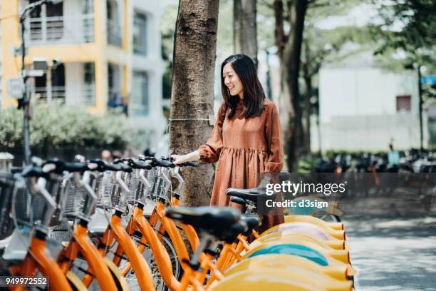 beautiful asian girl renting shared bicycle in city centre - taipei city bike sharing system stock pictures, royalty-free photos & images