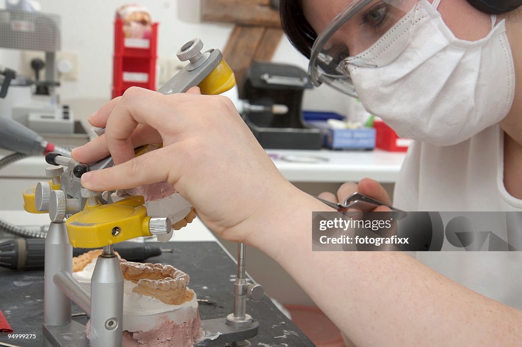 Female dental technician with surgical mask technician prepares a brace