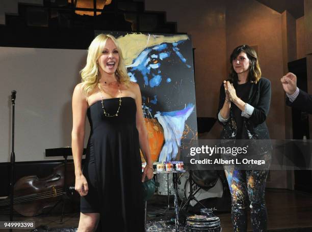 Lisa Arturo poses alongside her auctioned piece painted by Amy Burkman on stage at The Pawtastic Ball to benefit The Little Red Dog, Inc. Held at...