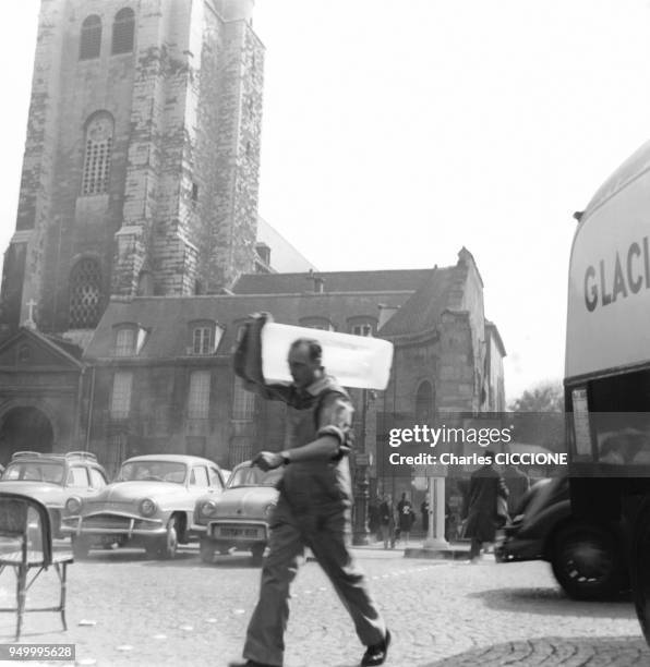 Un Livreur, tenant son pain de glace sur l'epaule, sur la place Saint-Germain-des-Pres circa 1960 a Paris, France.