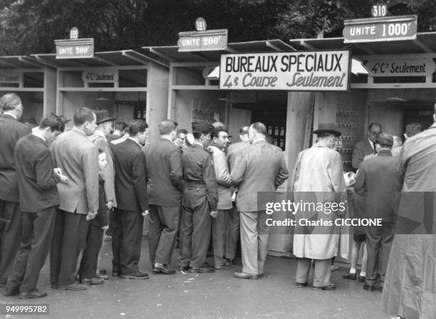 Parieurs dans la file d'attente devant les guichets d'un champ de courses, circa 1960 a Paris, France.