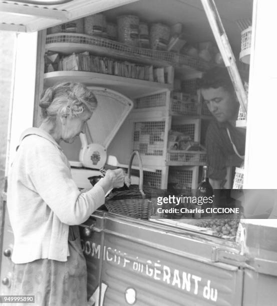 Une cliente regle ses achats a l'epicier, circa 1960 a Paris, France.