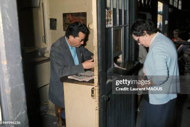 Une femme paye son entrée au marché du Carreau du Temple en mai 1976 à Paris, France.