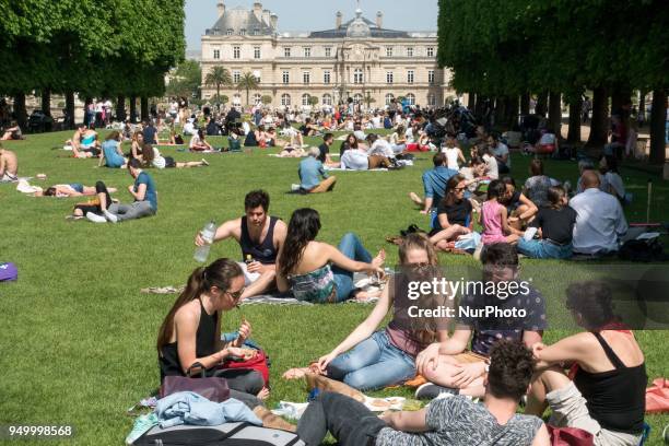 People relax on a warm weather Spring day in the Luxembourg garden in Paris, on April 22, 2018.