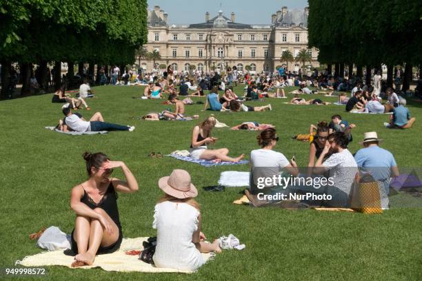 People relax on a warm weather Spring day in the Luxembourg garden in Paris, on April 22, 2018.