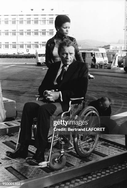 Richard Burton est poussé dans un fauteuil roulant par sa nouvelle compagne Jean Bell, le 10 mai 1975, à Nice, France.